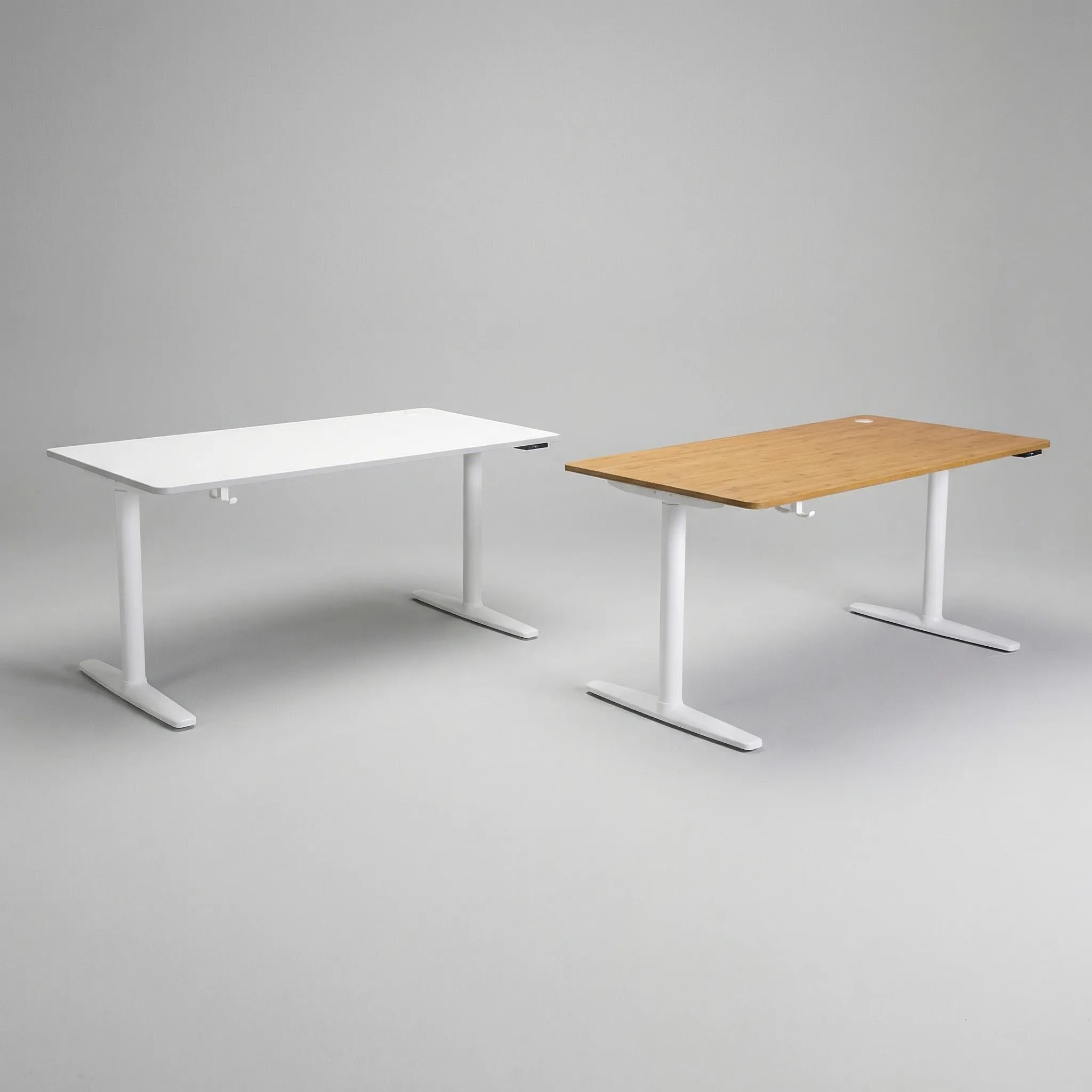 Zwei höhenverstellbare Schreibtische nebeneinander: links mit weißer Tischplatte, rechts mit Eiche-Dekor, beide mit weißem Stahlgestell